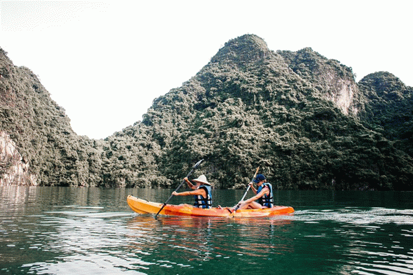 Два каякера плывут по водоему на фоне гор